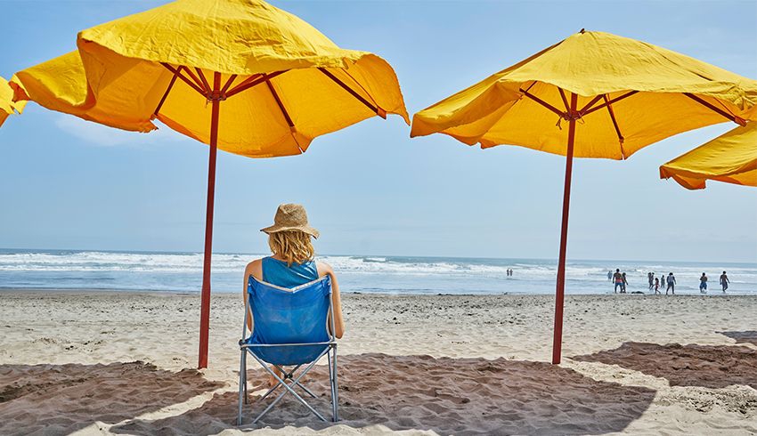 a woman under an umbrella on the beach